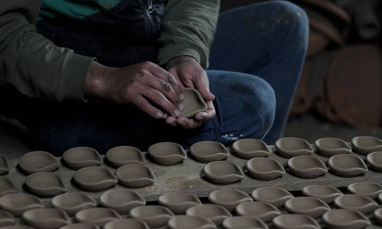 A potter clears oil lamps of dirt before putting them in ove to make them ready to use