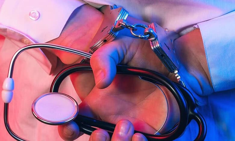 Handcuffed person holding a stethoscope, symbolising arrest of a fake doctor in Hyderabad hospital