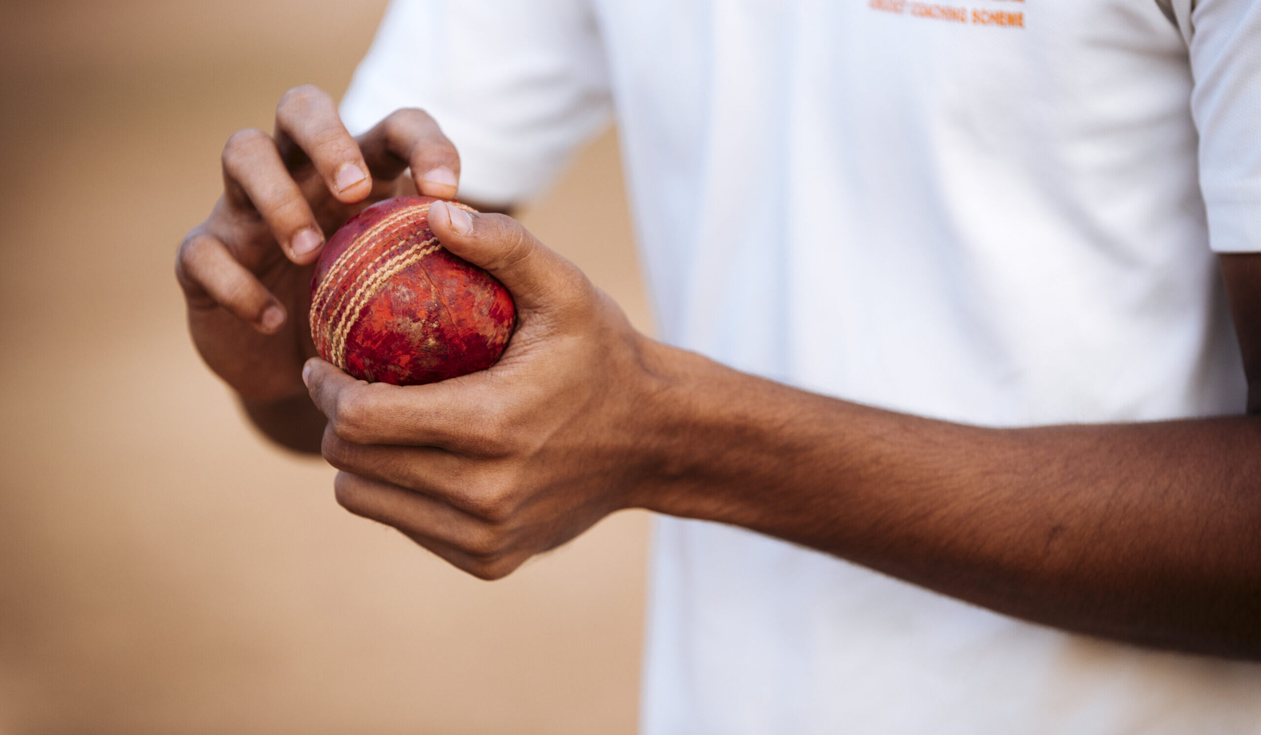 Cricketer holding a worn cricket ball ready to bowl