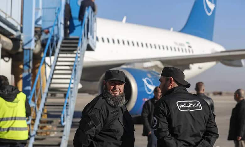 General Security personnel stand next to a Syrian Air airplane ahead of take-off as the airport reopens for internal flights in Damascus on Wednesday, December 18.