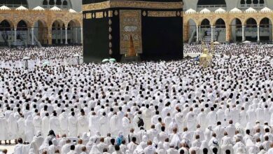 A vast congregation of Muslim worshippers, dressed in white ihram garments, gathers around the Kaaba at the Grand Mosque (Masjid al-Haram) in Makkah, Saudi Arabia, for the last Friday prayer of Ramzan. The sacred black-draped Kaaba stands at the centre, adorned with golden Arabic calligraphy.
