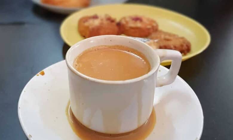 A cup of irani chai with biscuits in the background