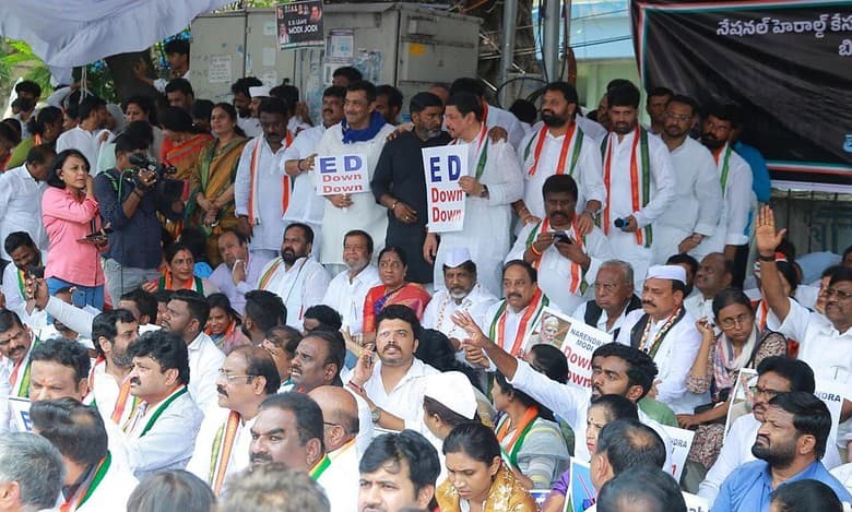 Telangana Congress leaders sitting in protest outside the Enforcement Directorate (ED) office in Hyderabad, holding placards and raising slogans.