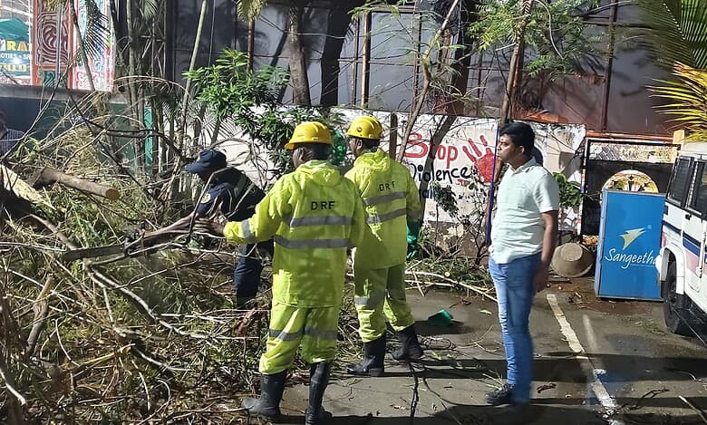 The image shows HYDRAA's DRF personnel removing a fallen tree in front of Saroornagar police station after the heavy rain on Friday evening, April 18, 2025.