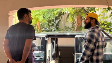 Two individuals stand outside a vehicle in a residential area