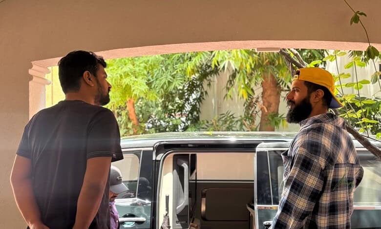 Two individuals stand outside a vehicle in a residential area