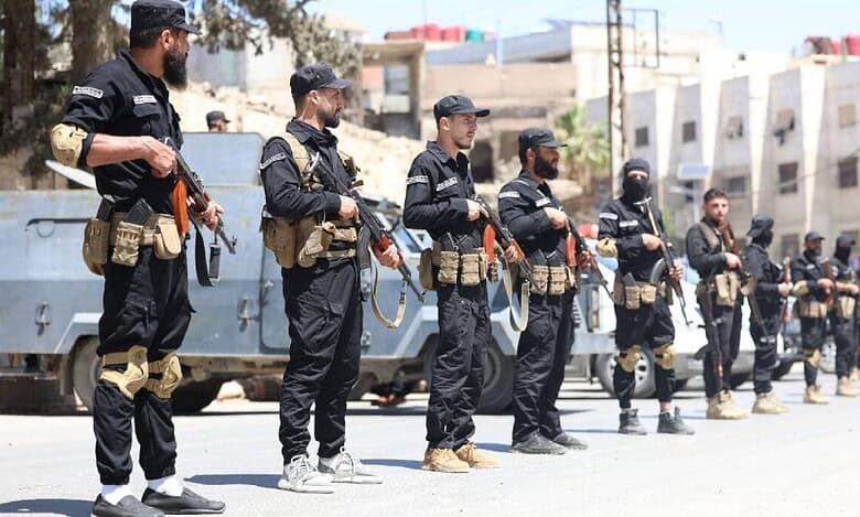 Syrian security forces in black uniforms standing in formation with rifles during a street deployment in a southern suburb of Damascus amid ongoing clashes.