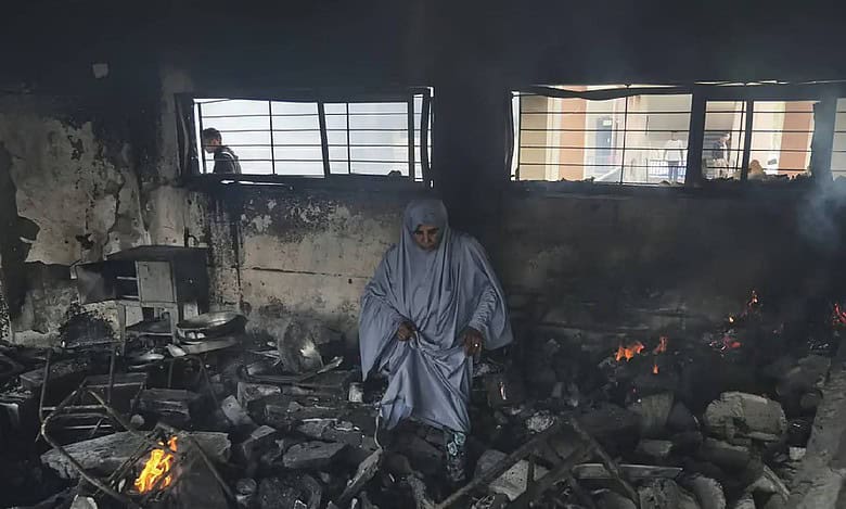 Palestinians inspect the rubble and debris at Yaffa school in Gaza City following an Israeli airstrike on April 23, 2025. The school building appears heavily damaged, with shattered concrete and twisted metal, as residents assess the destruction.