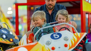 Father with two young children enjoying a car ride at Global Village Dubai funfair.