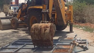 A JCB machine operated by HYDRAA demolishes an illegal gate blocking the road between Kandlakoya and Devrayanjal, clearing obstructions to restore access to National Highway 44.