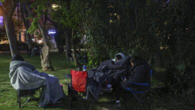 Istanbul residents wrapped in blankets and sitting on camping chairs in a park at night, seeking safety outdoors after a 6.2 magnitude earthquake and ongoing aftershocks.