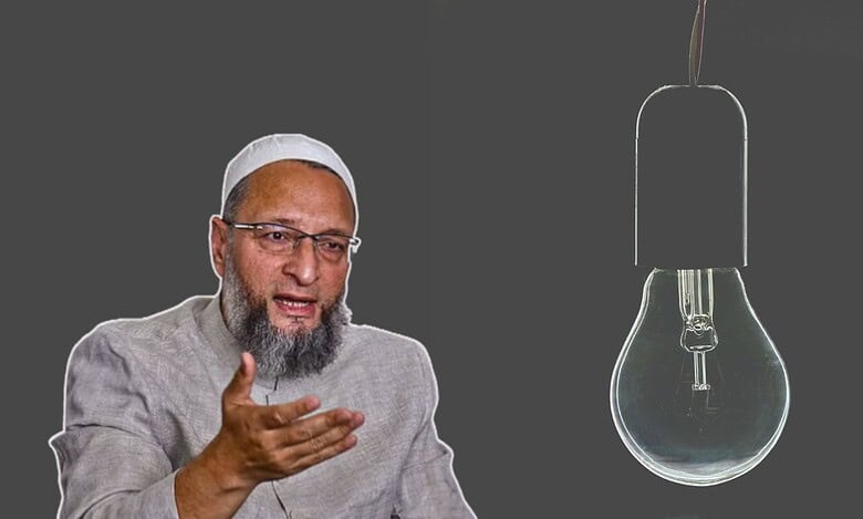 Asaduddin Owaisi wearing a light gray traditional outfit and white cap gestures with their hands against a dark background. To the right, a large, unlit light bulb is depicted.