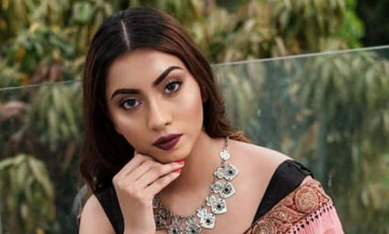 Meghna Alam, former Miss Earth Bangladesh, poses in traditional attire with statement jewellery, photographed outdoors against a natural green backdrop.