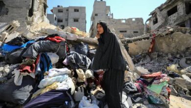 Palestinian woman stands on rubble, inspecting damage in Shujayea, Gaza, after Israeli forces withdraw following ground operation.