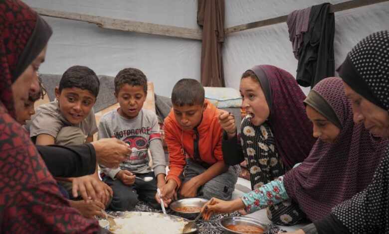 The Al-Najjar family shares a meal of peas and rice in their tent in Muwasi, near Khan Younis, southern Gaza Strip, Friday, April 25.