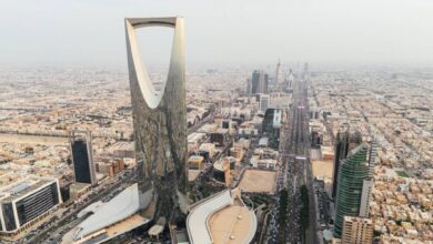 Aerial view of Riyadh city skyline, Saudi Arabia, featuring the iconic Kingdom Centre Tower and surrounding modern skyscrapers on a hazy day.