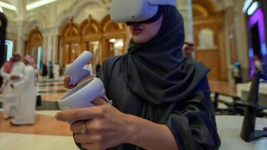 Saudi woman wearing VR headset and using controllers at a tech event in Riyadh