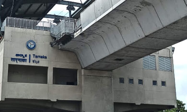 Concrete structure of Tarnaka Junction metro station with signage in Telugu and English, elevated platform above.