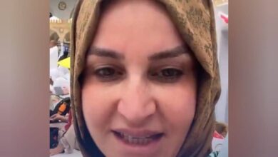 Close-up of a Turkish woman in a headscarf, speaking in front of the holy Kaaba at the Grand Mosque in Makkah.