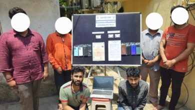 Six individuals, including two kneeling in front, are seen near a display board labeled "Commissioner's Task Force, Hyderabad City Police, Central Zone." The board shows seized items including smartphones, fake Aadhaar cards, a Bangladesh passport copy, and forged birth certificates