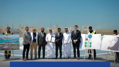 Officials pose at the site of the UAE’s first hybrid heliport at Zayed Port, Abu Dhabi, with development plans displayed on easels.