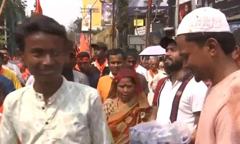 A Ram Navami devotee smiles at a Muslim man as he accepts a bottle of water from him in West Bengal on Sunday