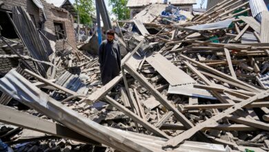The image displays a man standing between the remains of a demolished house in Kashmir. April 26, 2025