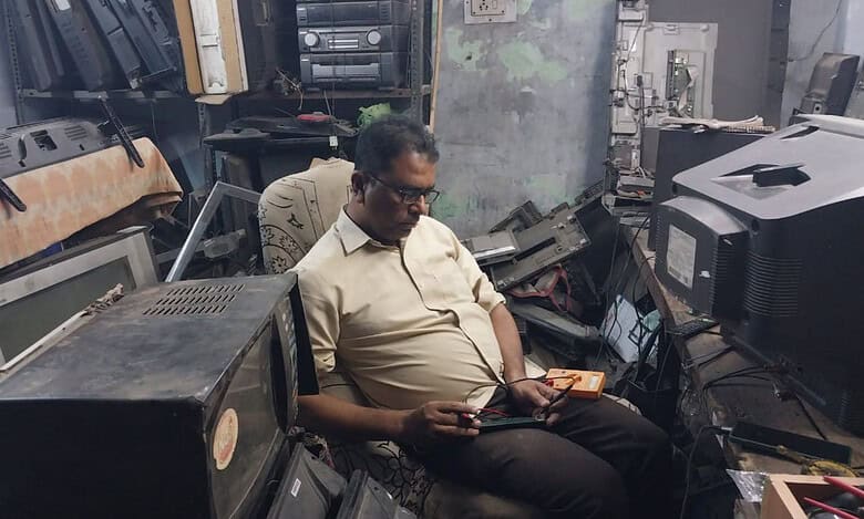 The image displays a picture of a man named Mohd Abdul Ishaq repairing old television sets in Hyderabad. April 26, 2025