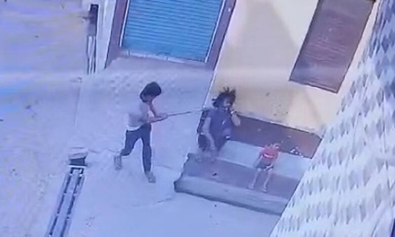 The image displays a man attacking another with a axe. A child is sitting besides them. April 28, 2025