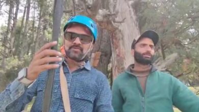 The image shows two persons, one a zipline operator and the other a tourist in Pahalgam.