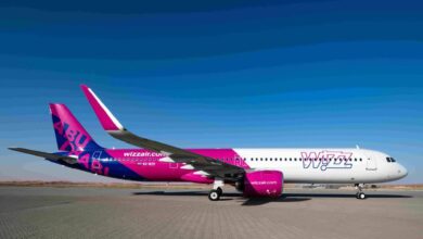 Wizz Air Abu Dhabi aircraft on runway in desert backdrop under clear sky.
