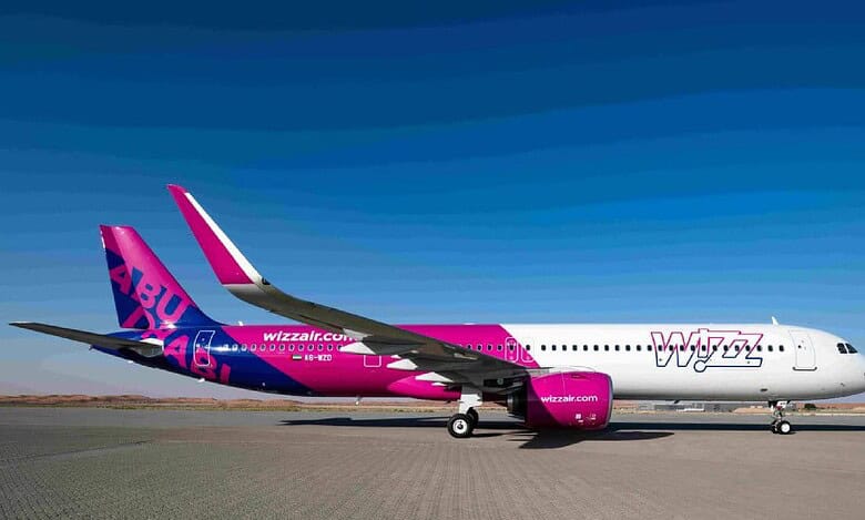 Wizz Air Abu Dhabi aircraft on runway in desert backdrop under clear sky.
