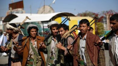 Armed Houthi fighters stand in a row in Sanaa, Yemen, carrying rifles and traditional Yemeni daggers.