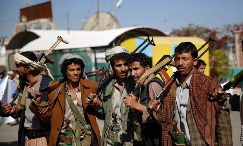 Armed Houthi fighters stand in a row in Sanaa, Yemen, carrying rifles and traditional Yemeni daggers.