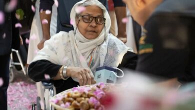 Elderly female Haj pilgrim in wheelchair welcomed with rose petals and traditional dates on arrival in Saudi Arabia for Haj 2025.