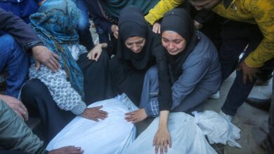 Grieving Palestinian women mourn beside bodies wrapped in shrouds after Israeli strikes in Gaza.