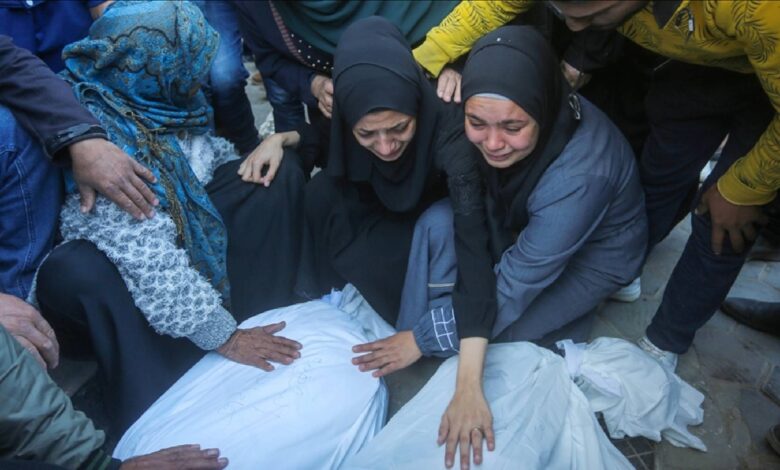 Grieving Palestinian women mourn beside bodies wrapped in shrouds after Israeli strikes in Gaza.