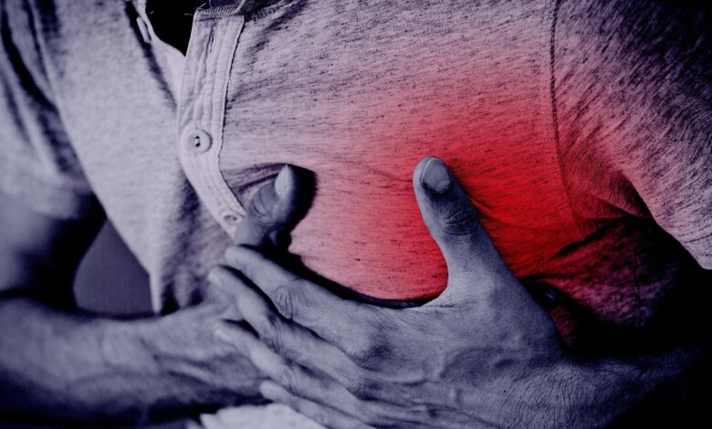 Representational image of a man clutching his chest and collapsing on a cricket field due to cardiac arrest.