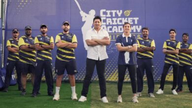 Smriti Mandhana with coach Don Bhagawati and the coaching team at the launch of City Cricket Academy by Smriti Mandhana in Dubai, standing in front of the academy banner on a cricket ground.