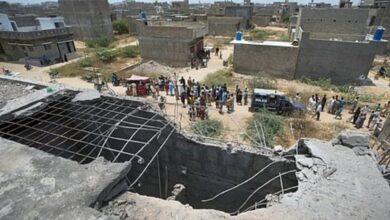 A large hole is visible on the rooftop of a structure reportedly damaged in a suspected Indian drone strike, as residents gather near a cordoned-off area where Pakistan's air defence system shot down the drone in Karachi on May 8.