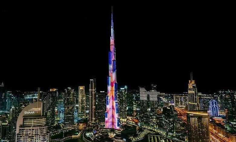 Night view of Burj Khalifa illuminated with colourful LED lights, surrounded by the glowing skyline of Downtown Dubai, UAE.
