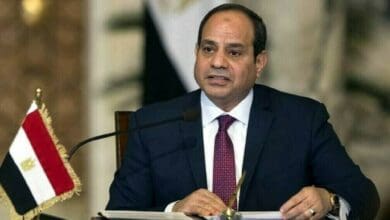 Egyptian President Abdel-Fattah al-Sisi speaks during an official meeting, seated at a desk with the Egyptian flag beside him.