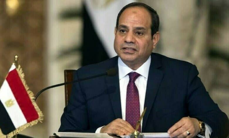 Egyptian President Abdel-Fattah al-Sisi speaks during an official meeting, seated at a desk with the Egyptian flag beside him.