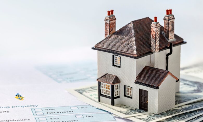 A model of a house placed on US dollar bills, with property-related documents underneath, symbolising property ownership, real estate investment, or property tax payments for GHMC property tax collection story.