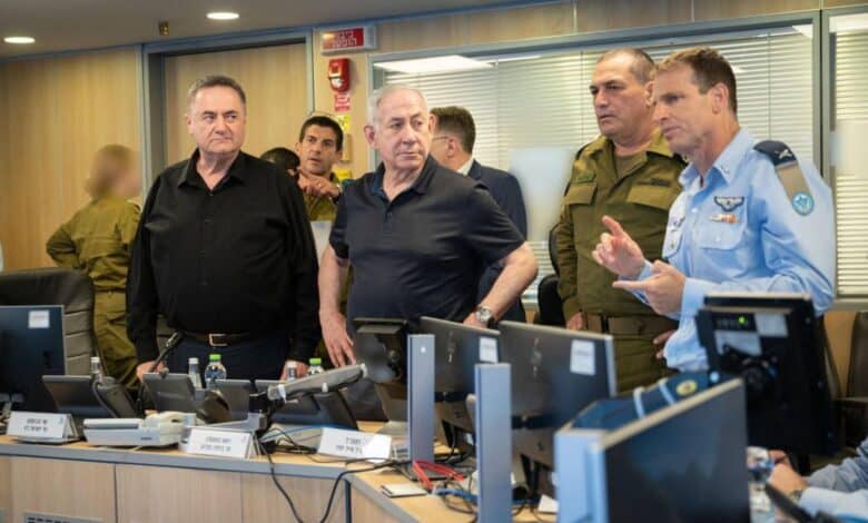 A group of officials in a control room with computers, discussing strategy. Some wear military uniforms, others casual attire, in a serious meeting setting.