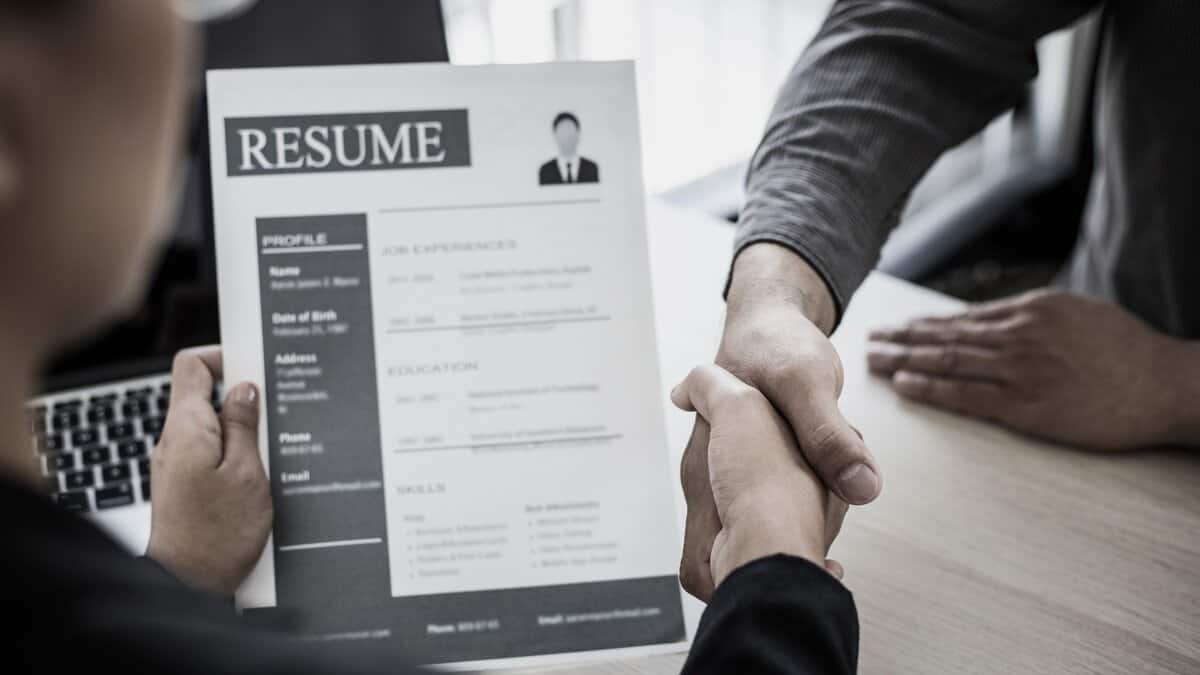 Representational Image of two men shaking hands while other one holds resume for jobs in Germany