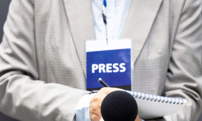 Representational Image of man wearing press ID and holding a mic