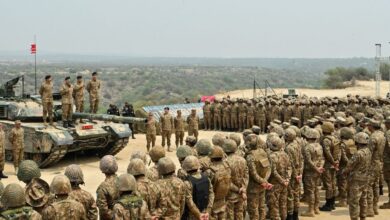 Pakistani soldiers gather around tanks during a military exercise in a desert area with senior officers.