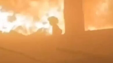 Palestinian girl silhouetted against flames inside a bombed classroom in Gaza