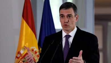 Spanish Prime Minister Pedro Sanchez speaks at a podium with the Spanish and European Union flags in the background.
